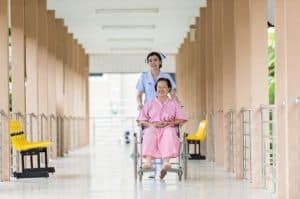 Medical Assistant working in hospital transporting patient in wheelchair